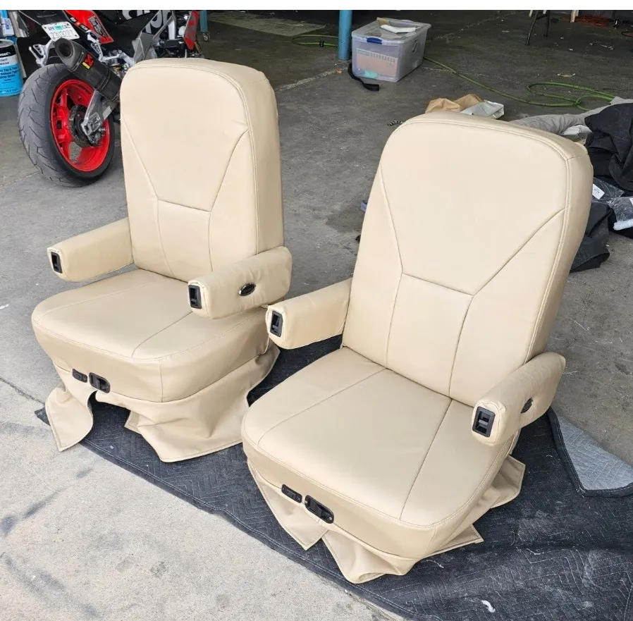 Pair of beige leather seats sitting on top of a black mat on the floor, with a motorcycle, a bucket