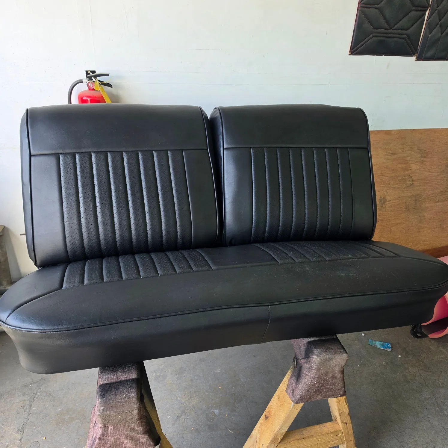 Black leather seat on a wooden stand in a garage, with a fire extinguisher