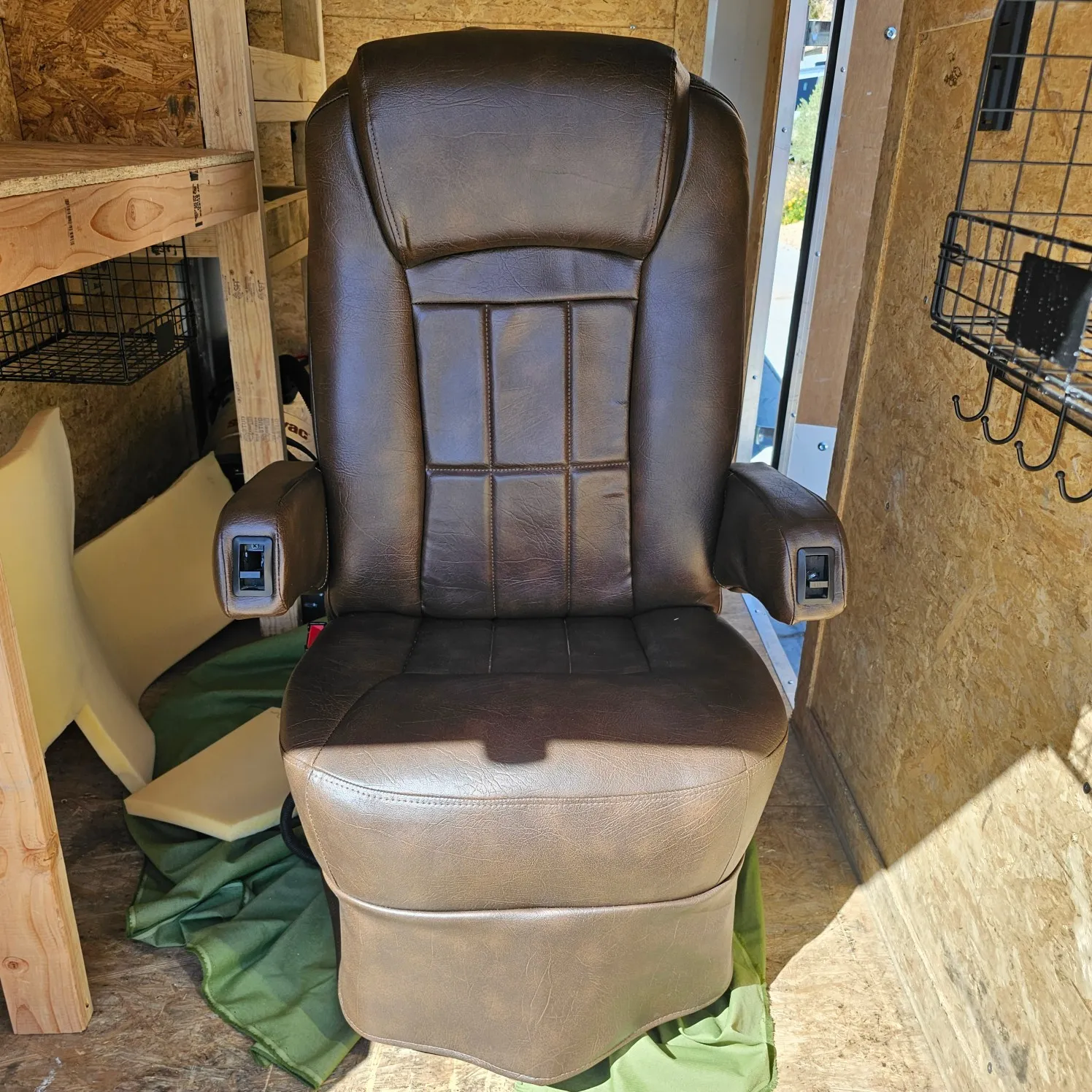 Brown recliner chair sitting atop a green cloth in a room with a wooden wall on the right side