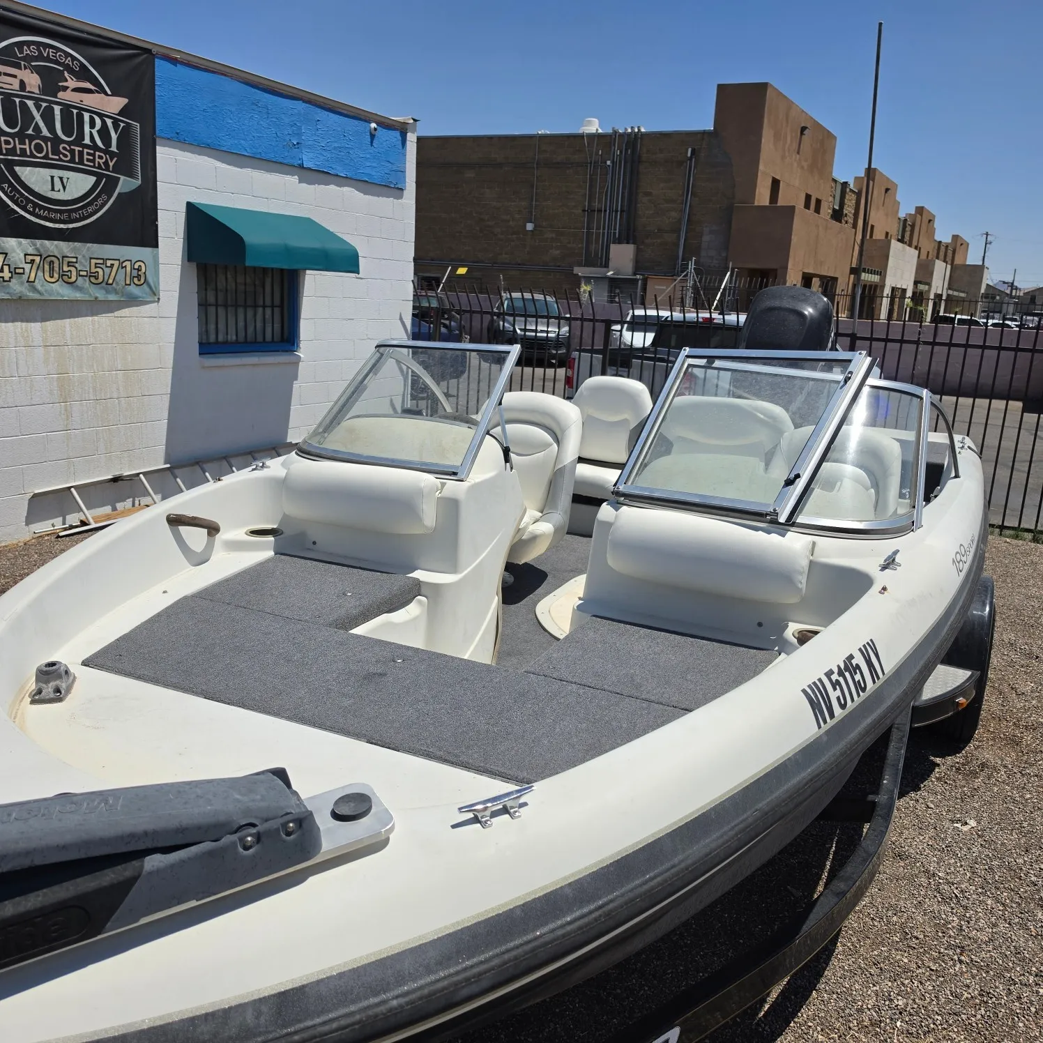 White boat parked in front of a building with a banner on the wall