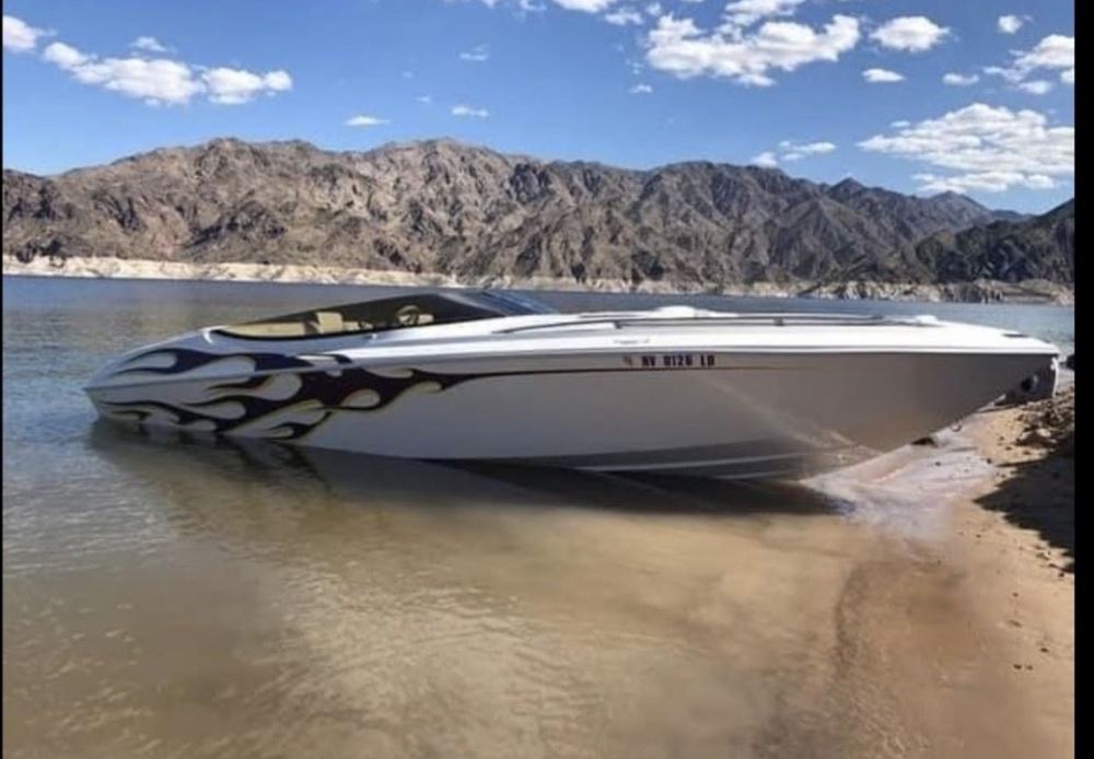 White and black speed boat, the new, sitting on top of a sandy beach with mountains in the background